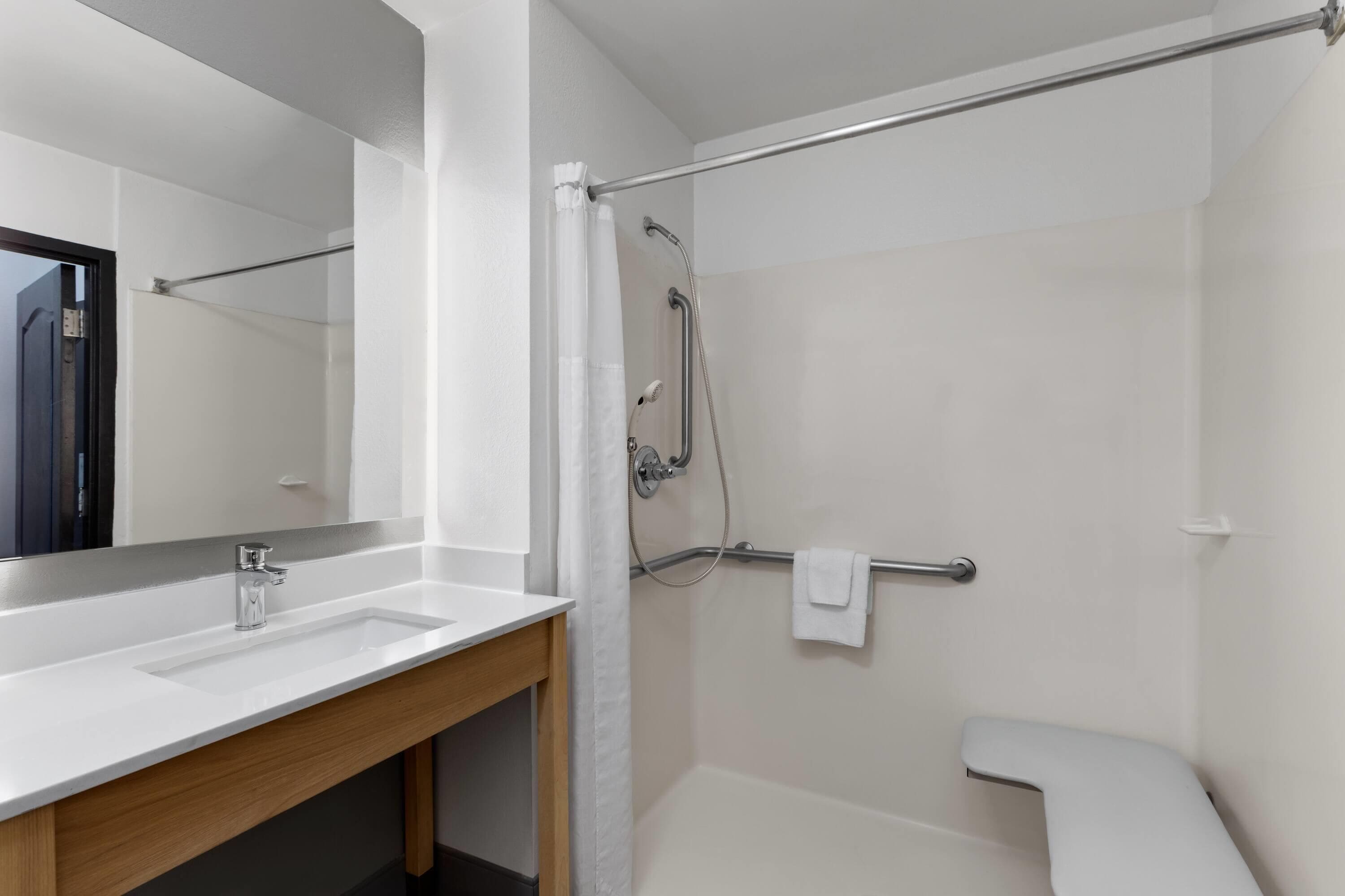Uma casa de banho moderna com lavatório branco, espelho e área de duche.