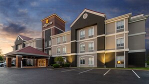Un hotel de varios pisos con un letrero llamativo de 'LaQuinta', una entrada cubierta y un estacionamiento.