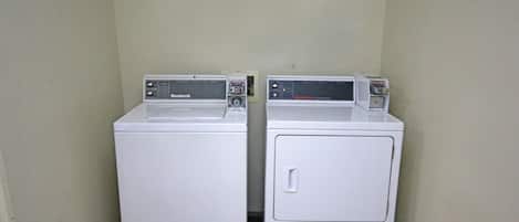 Two white front-loading washing machines in a corner with a tiled floor.