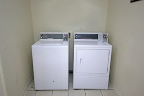 Two white front-loading washing machines in a corner with a tiled floor. - Red Roof Inn Gaffney (Gaffney)
