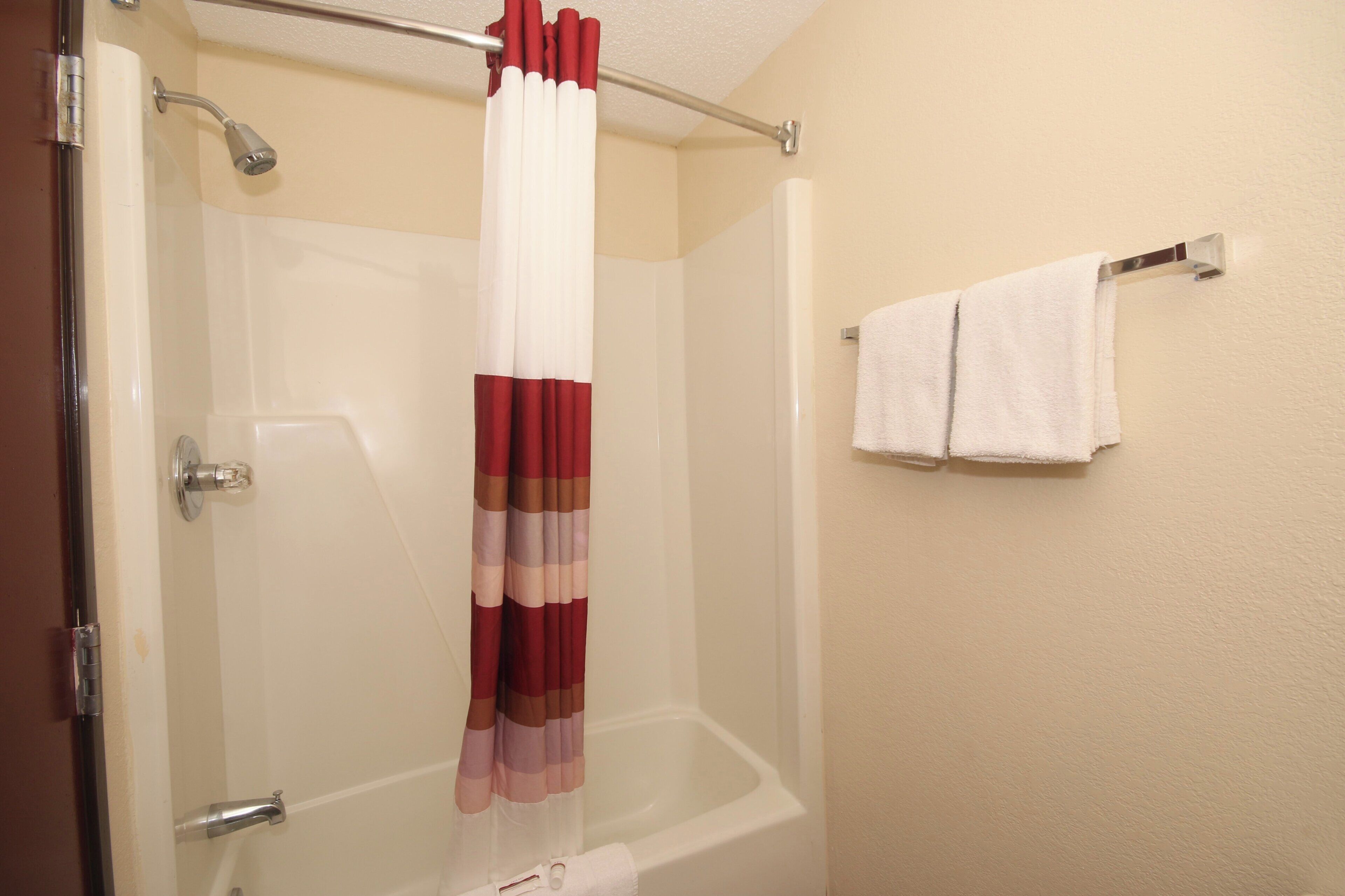 A bathroom with a shower curtain, a bathtub, and two towels on a rack.