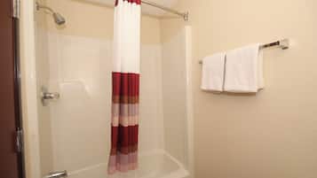 A bathroom with a shower curtain, a bathtub, and two towels on a rack.