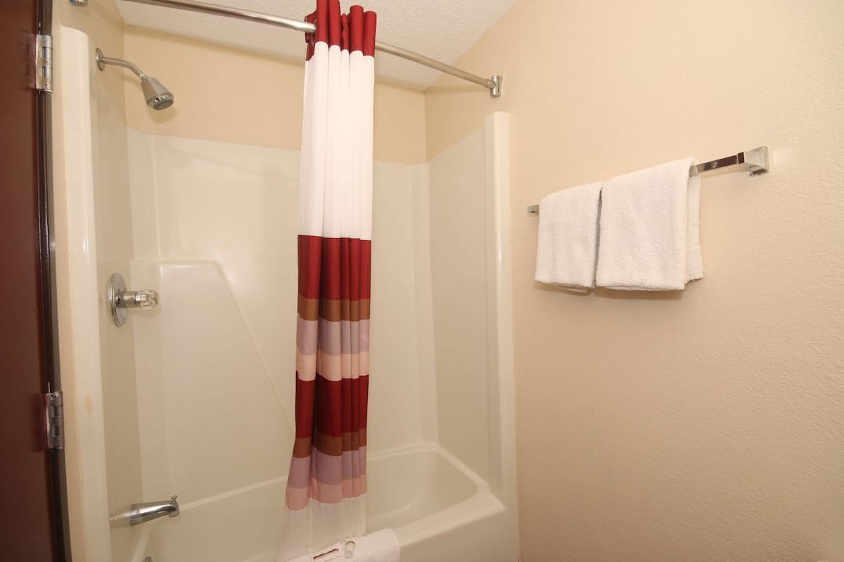 Ein Badezimmer mit Duschvorhang, Badewanne und Handtuchhalter mit zwei Handtüchern.