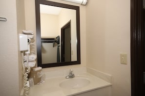 A bathroom with a white sink, a mirror, and a towel dispenser.