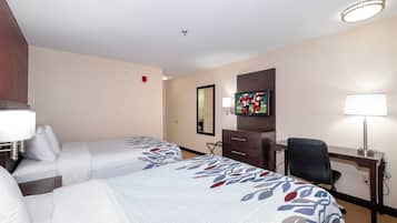 Habitación de hotel con dos camas, un escritorio, una silla, un televisor y un espejo.