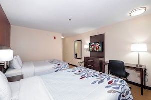 Habitación de hotel con dos camas, un escritorio, una silla, un televisor y un espejo.