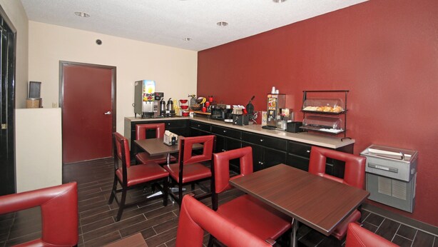 A restaurant with red chairs and a counter with food items. - Red Roof Inn Gaffney (Gaffney)