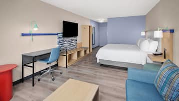 Ein Hotelzimmer mit Bett, Schreibtisch, Stuhl, Fernseher und einem roten Mülleimer.