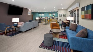 Un hall d’hôtel moderne, doté d’espaces de détente, d’une cuisine et d’un écran de télévision.
