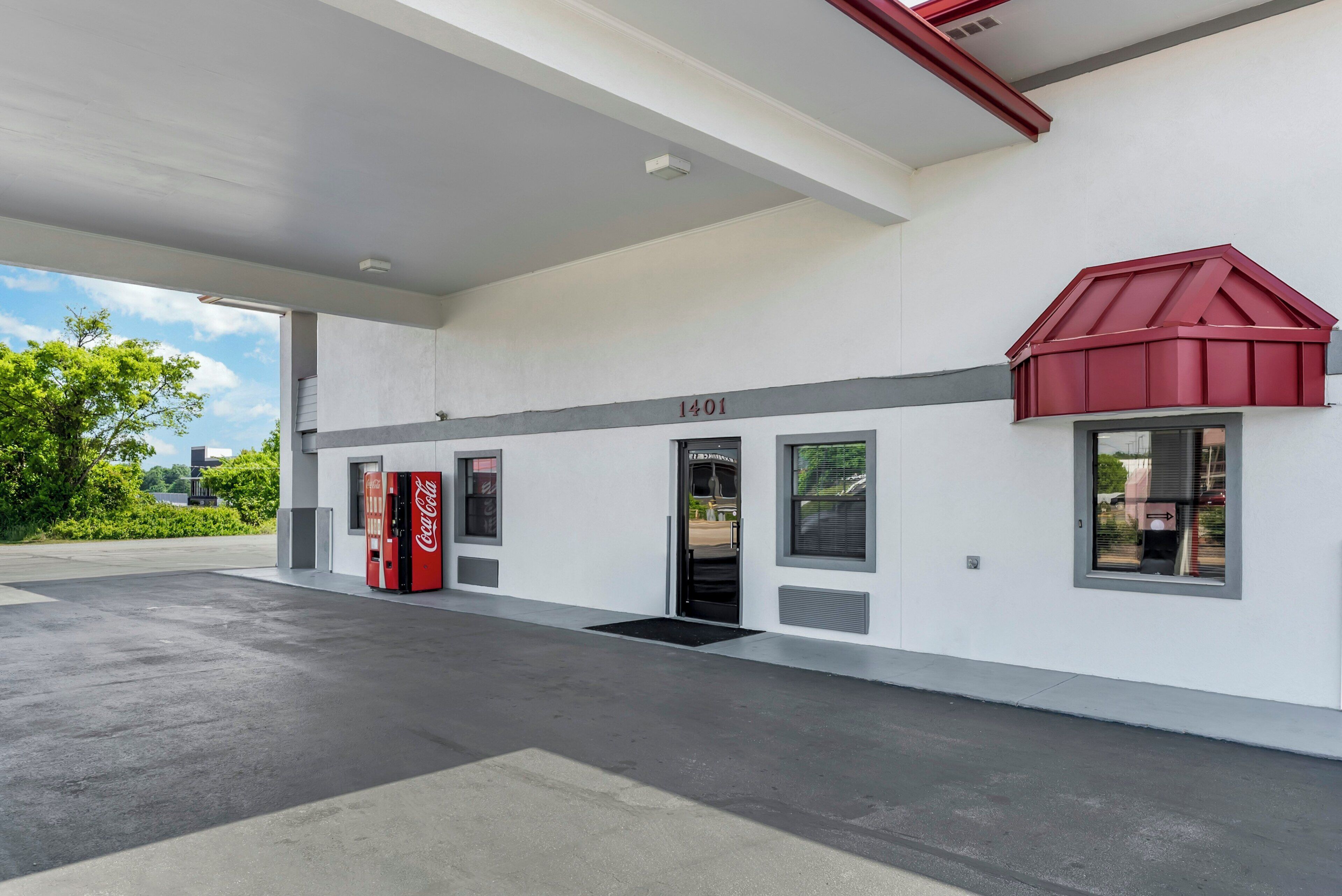 A gas station with a Coca-Cola vending machine, a red awning, and a number '1401' on the wall.