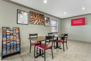 A conference room with tables and chairs, framed pictures on the walls, a bulletin board with brochures, and a sign indicating free Wi-Fi. - Red Roof Inn West Memphis, AR (West Memphis)