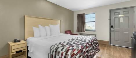 Una habitación de hotel con cama, mesita de noche, silla, ventana y puerta.
