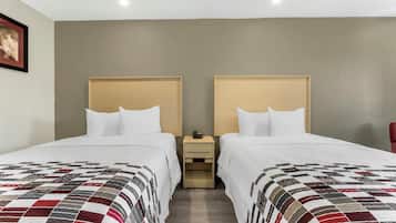 A hotel room with two beds, a nightstand, and a framed picture on the wall.