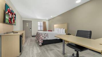 Une chambre d’hôtel avec un lit, un bureau, une chaise et un téléviseur fixé au mur.
