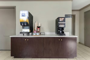 A counter with a coffee machine, a juice dispenser, and a sign for an ice machine.