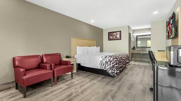 A hotel room with a bed, a red sofa, a desk, and a mirror.