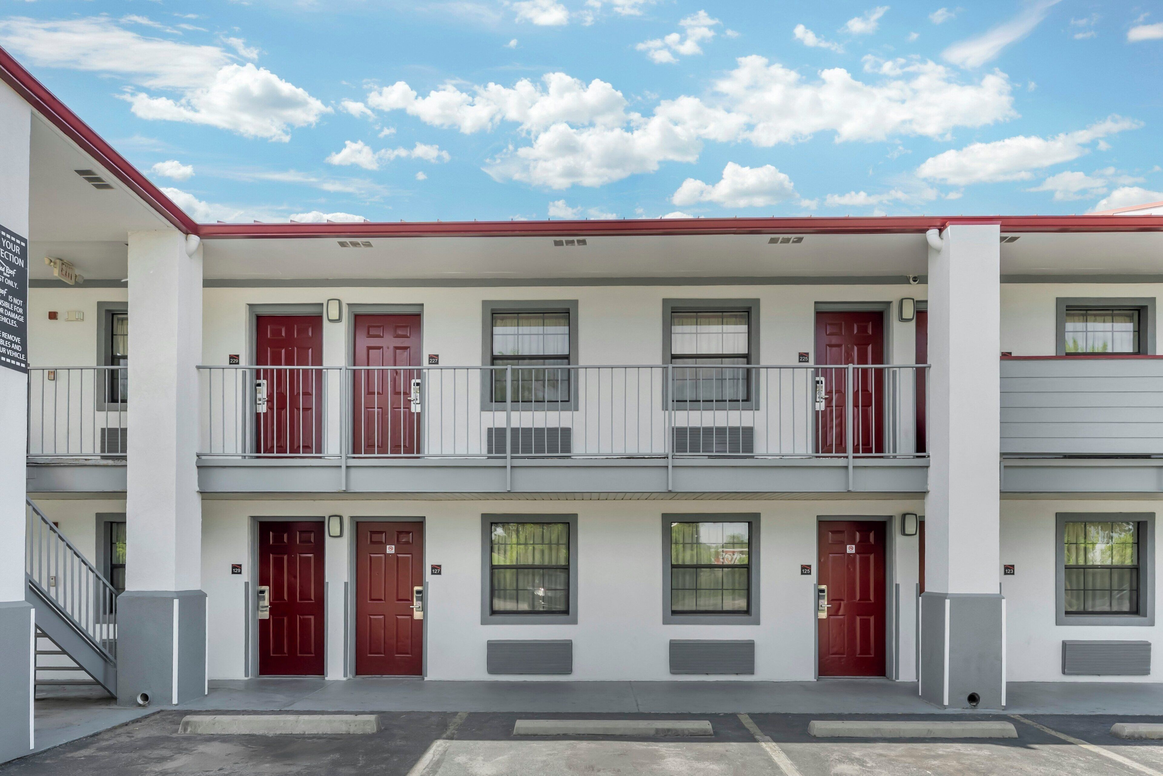 A multi-story building with red doors, windows, and a balcony.