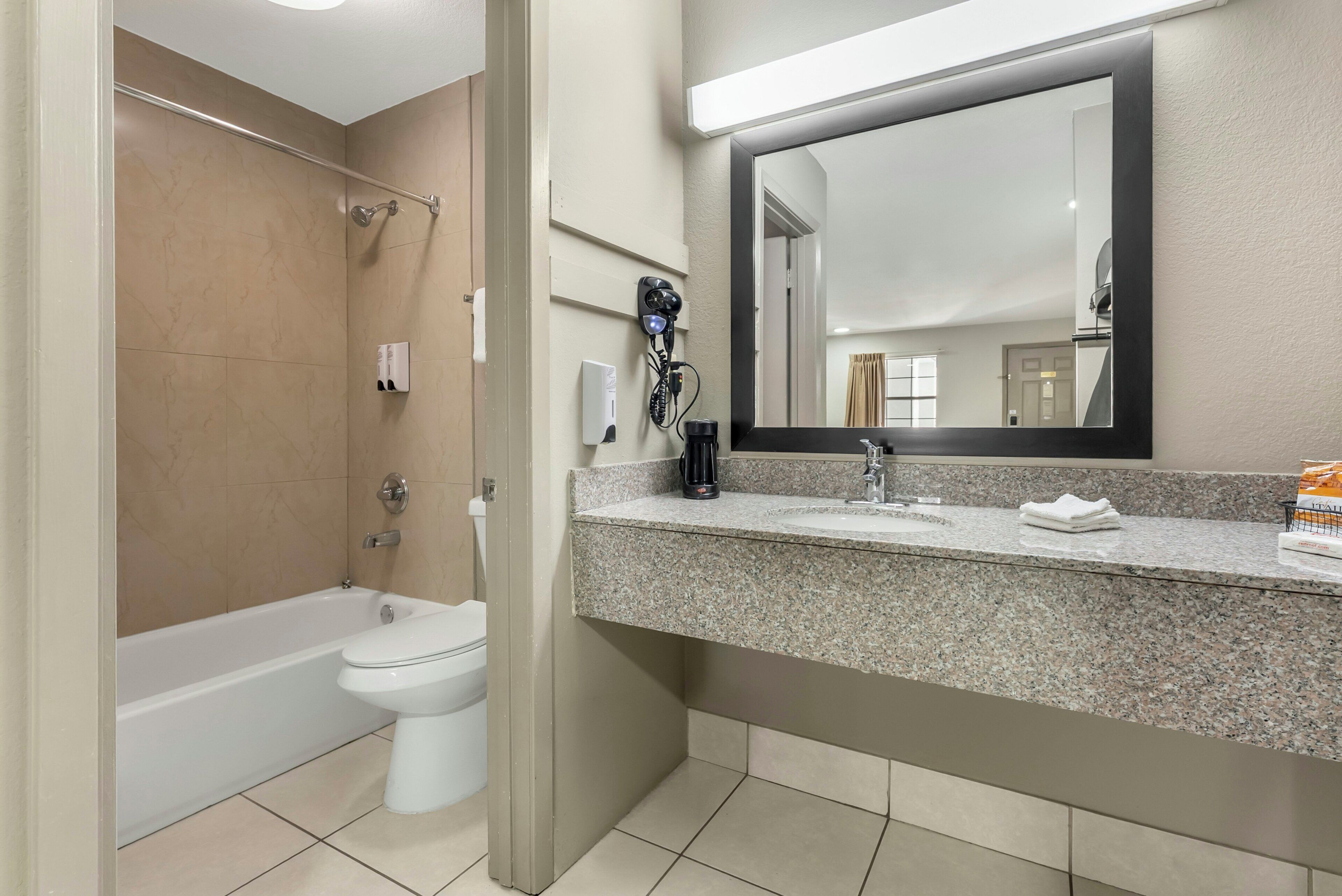 A bathroom with a bathtub, toilet, sink, and a large mirror.