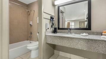 A bathroom with a bathtub, toilet, sink, and a large mirror.