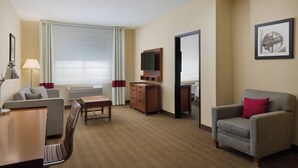 A hotel room with a sofa, armchair, TV, and a desk. - Four Points By Sheraton Portland East (Portland)