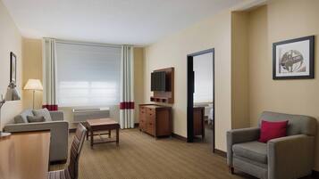 Une chambre d’hôtel équipée d’un canapé, d’un fauteuil, d’une télévision et d’un bureau.