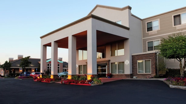 A modern hotel with a covered entrance, multiple floors, and a landscaped front yard with flowers. - Four Points By Sheraton Portland East (Portland)