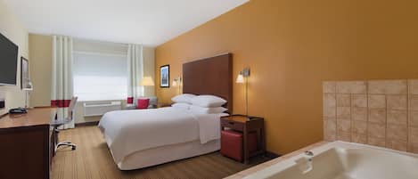 Quarto de hotel com cama, escrivaninha, cadeira, luminária de mesa, mesa de cabeceira, abajur, janela com cortinas, TV fixada na parede e banheira.
