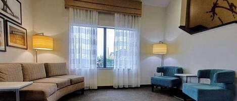 Una sala de estar con un sofá, dos sillones, una mesa de centro y dos lámparas.