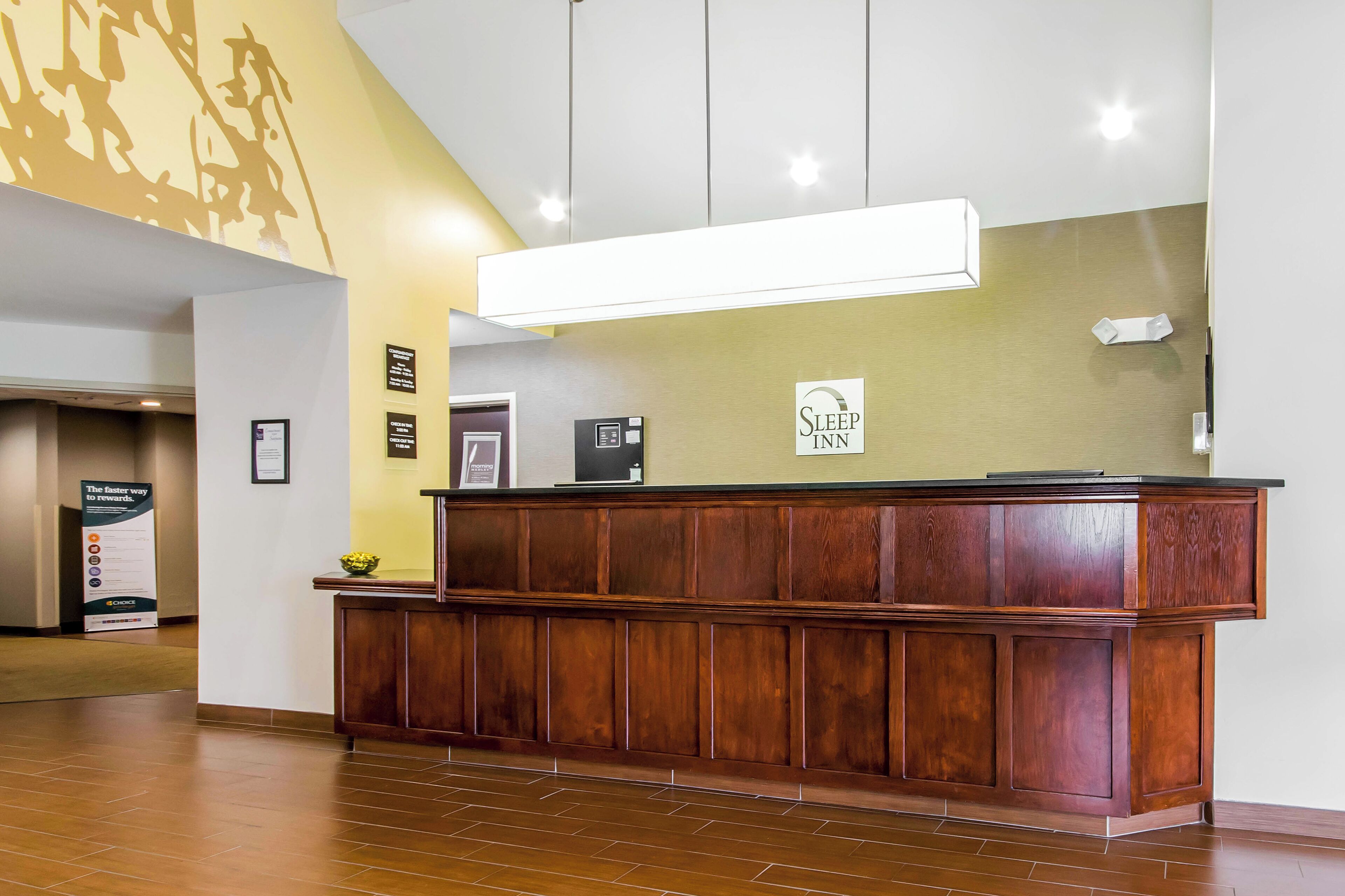 A reception desk with a wooden finish, a sign for 'Sleep Inn', and a wall-mounted light fixture.