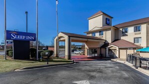 L’entrée d’un hôtel Sleep Inn, avec un ciel dégagé, un mât de drapeau et un parking.