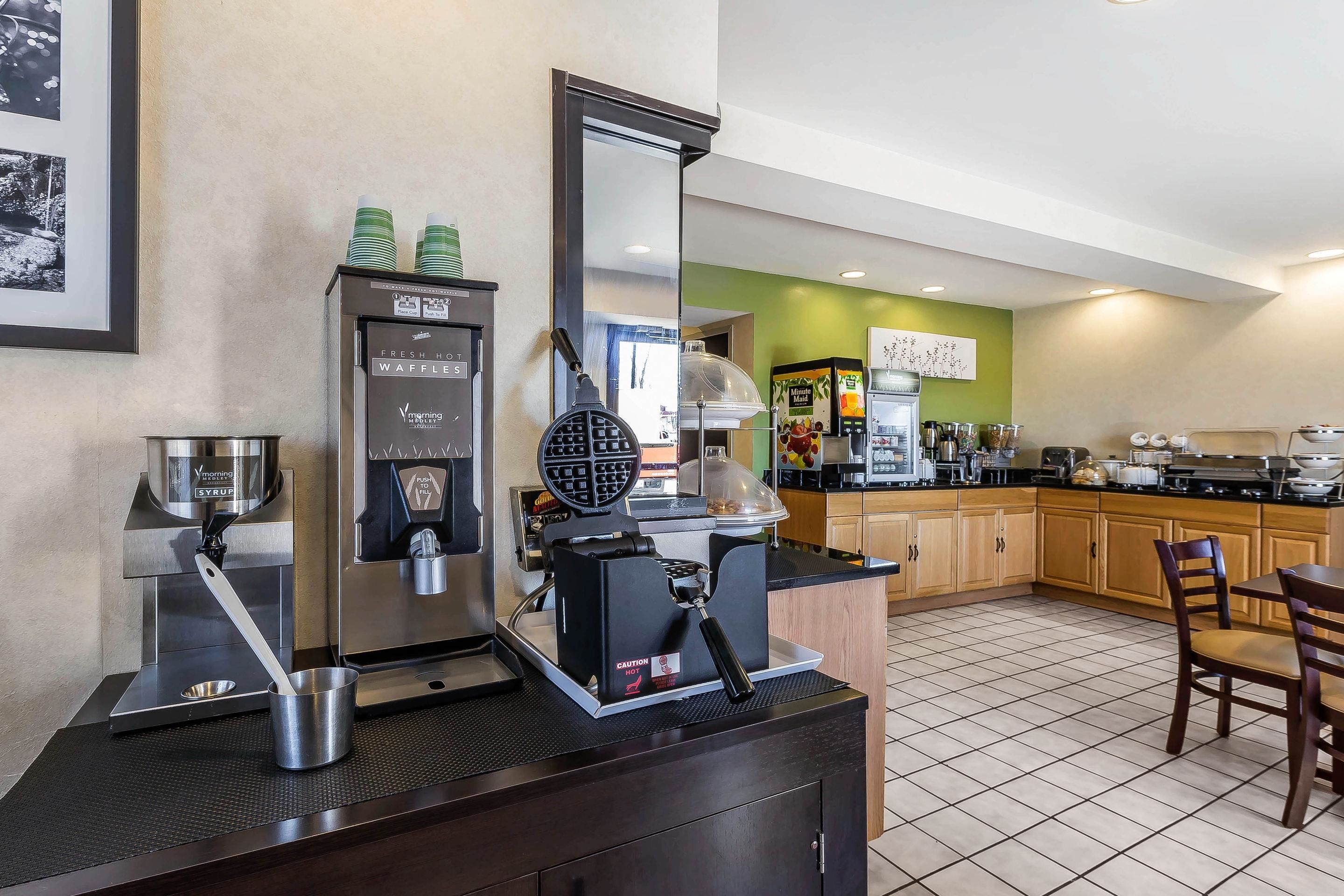 A modern kitchen with a waffle maker, coffee machine, and a kettle.