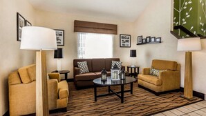 Un salon comprenant un canapé, deux fauteuils, une table basse et un tapis à motifs.