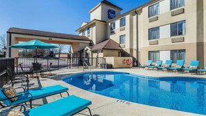 Un hôtel doté d’une piscine, de chaises longues et d’un espace salon abrité.