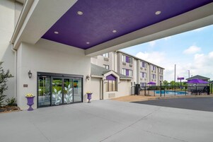 A hotel entrance with a covered walkway, a pool area, and a sign for a spa.