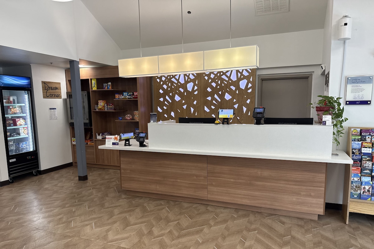 A reception desk with a modern design, a refrigerator, and a plant.