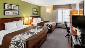 Une chambre d’hôtel avec deux lits, un bureau avec une télévision et une fenêtre avec des rideaux.