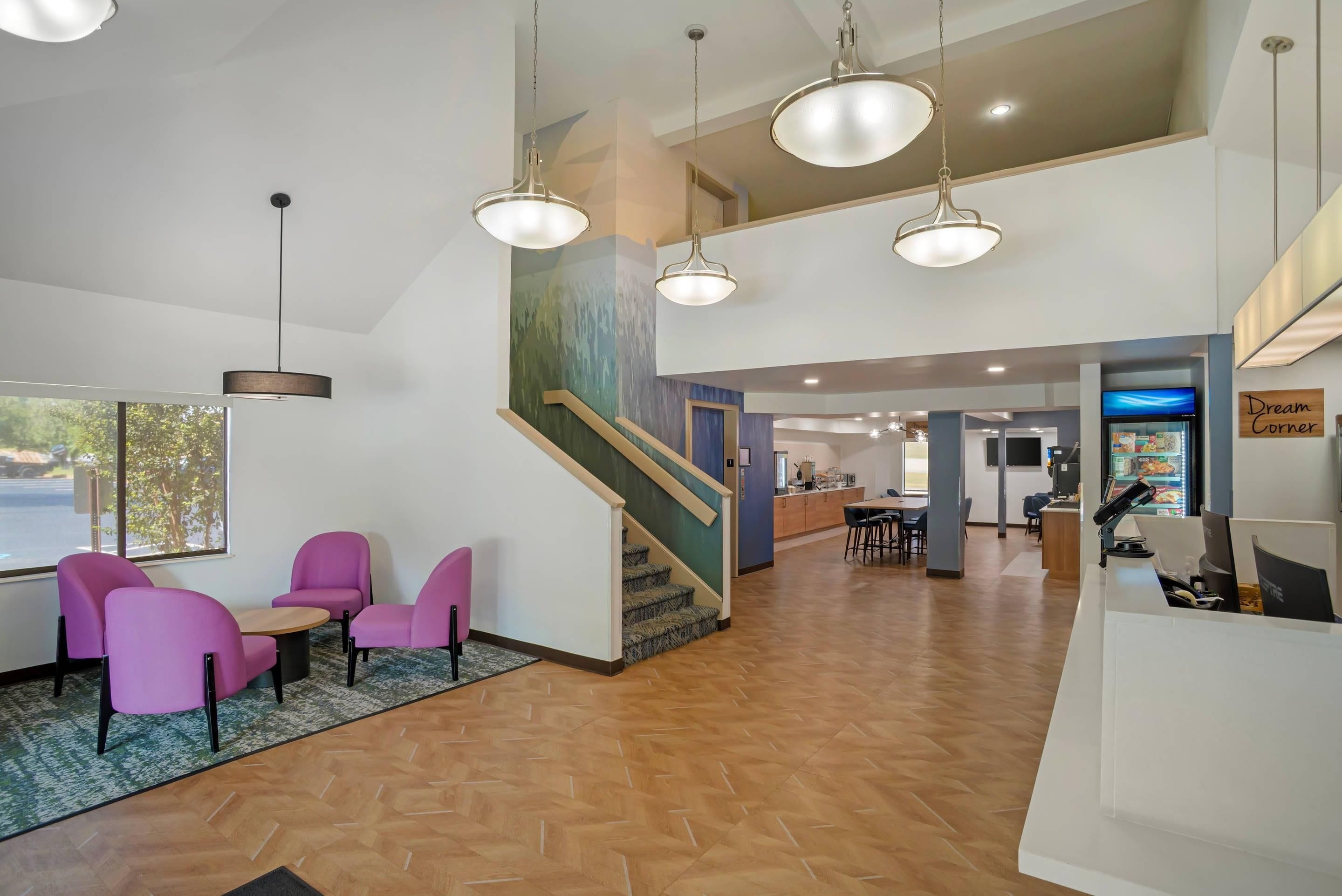 A hotel lobby with a reception desk, a staircase, and seating area.