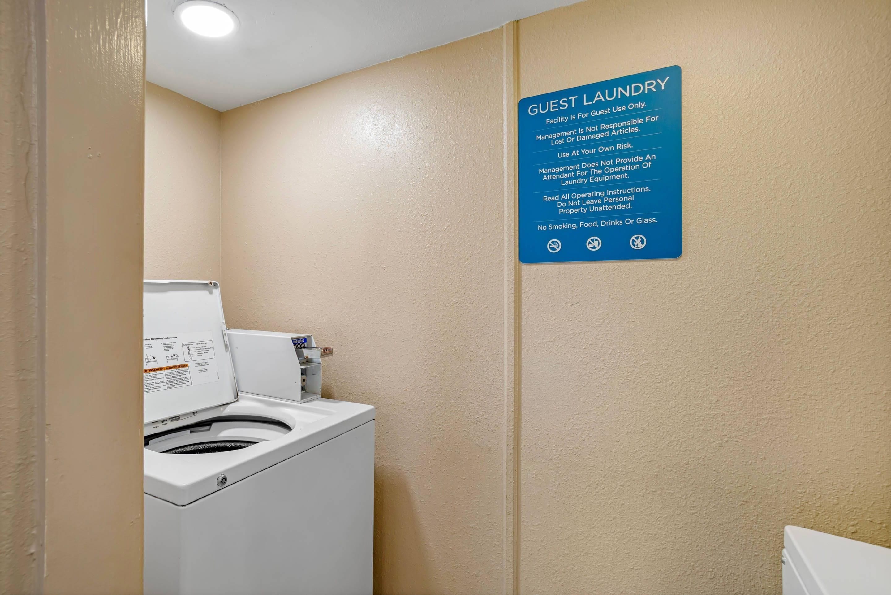 Een wasserette voor gasten met een wasmachine en een bord met instructies en regels voor gebruik.