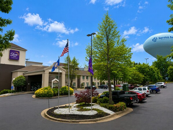 A hotel with a parking lot, a large water feature, and flags. - Sleep Inn Woodbridge - Potomac Mills (Woodbridge)
