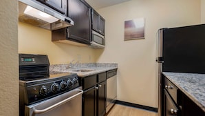 A compact kitchen with a stove, oven, microwave, and a refrigerator.