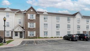 A multi-story hotel with a brick facade and white siding, featuring a parking lot with marked spaces.