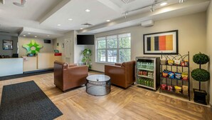 A reception area with a desk, seating, a television, a vending machine, and a window with a view.