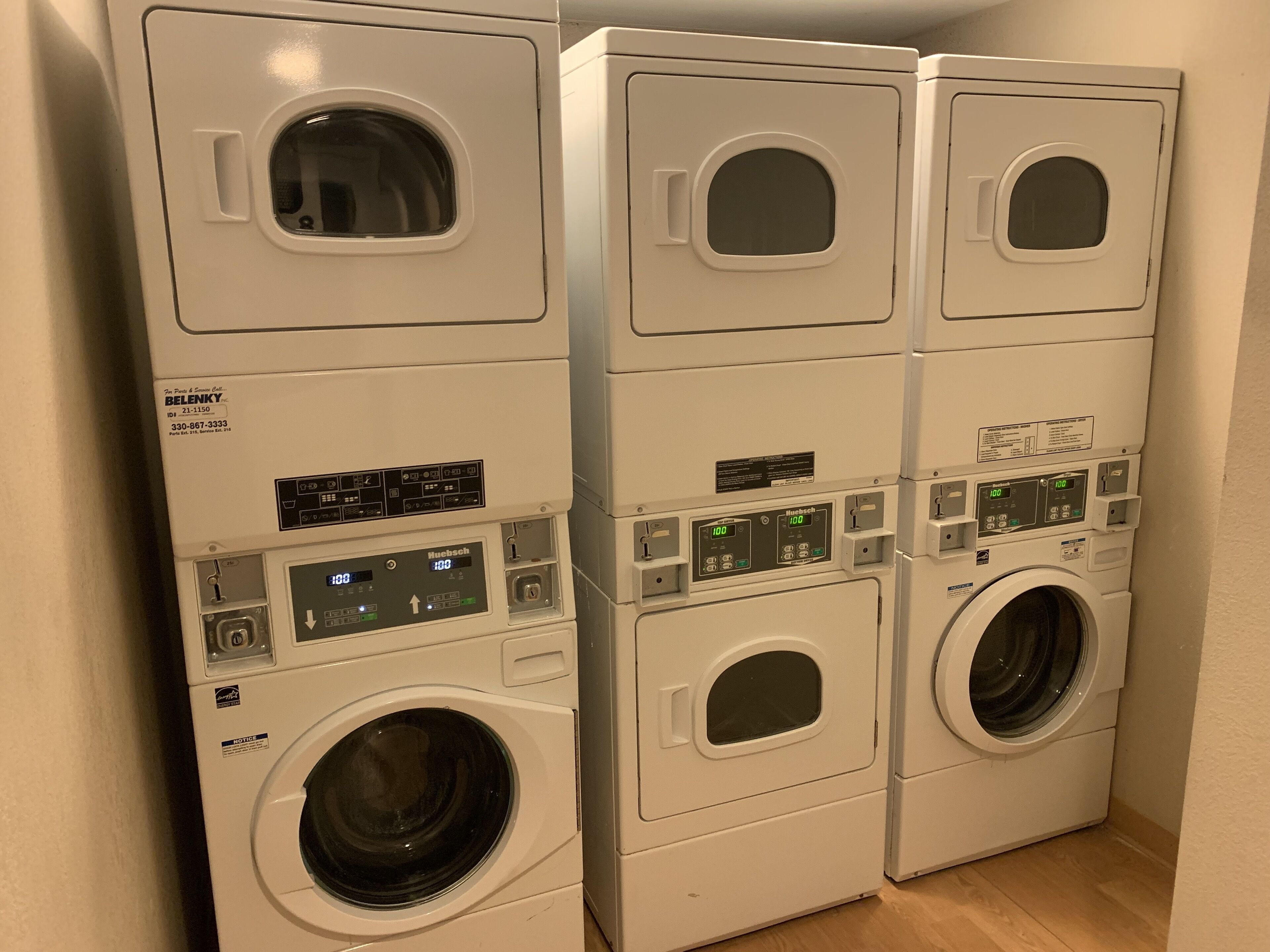 Une rangée de machines à laver à chargement frontal, empilées les unes sur les autres, avec leurs panneaux de commande et un écran numérique.