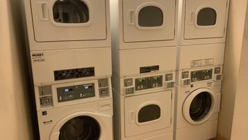 Une rangée de machines à laver à chargement frontal, empilées les unes sur les autres, avec leurs panneaux de commande et un écran numérique.