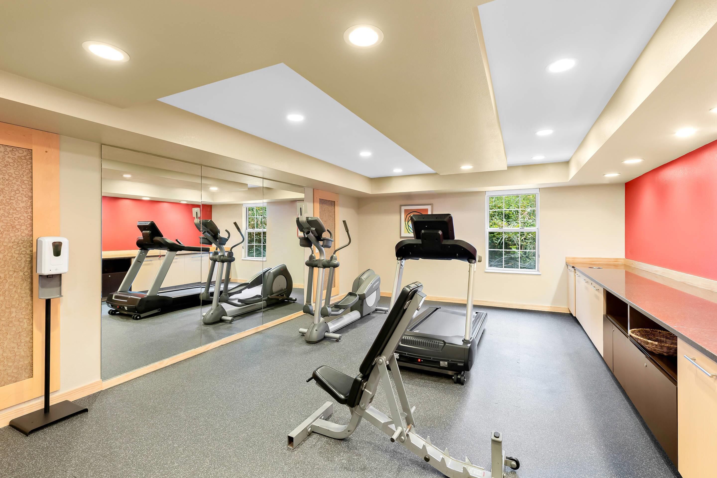 Un gimnasio con cintas de correr, elípticas y bancos de pesas.
