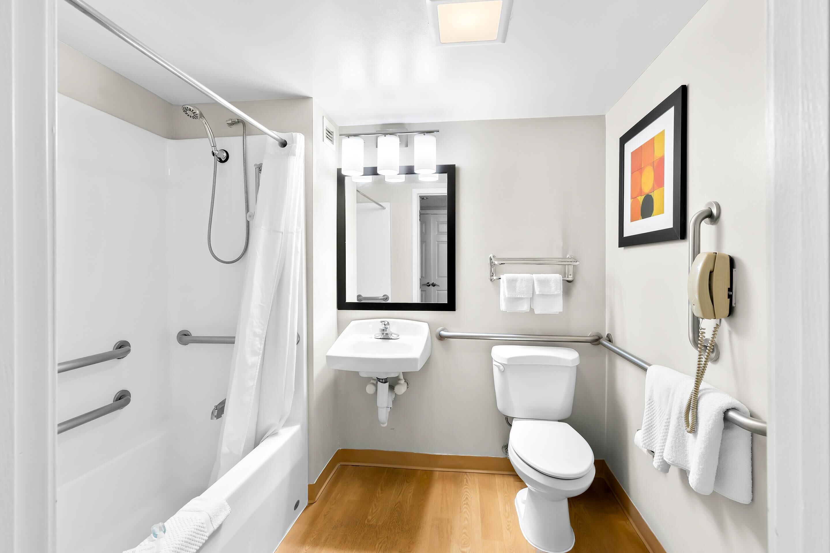 Un baño pequeño con ducha, inodoro, lavamanos y teléfono.