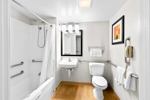 Un baño pequeño con ducha, inodoro, lavamanos y teléfono.