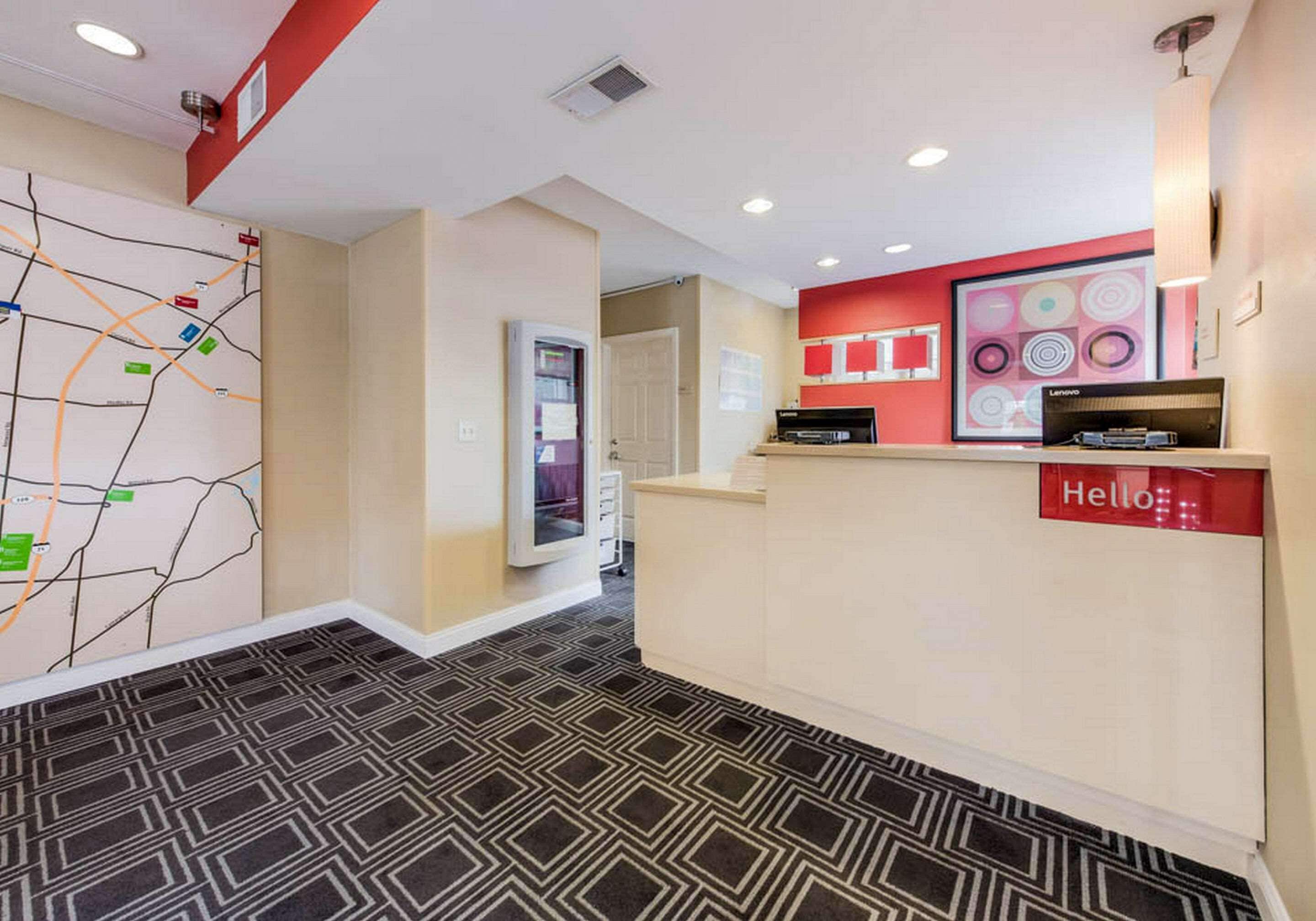 A hotel reception area with a map on the wall, a reception desk, and a "Hello" sign.