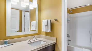 A bathroom with a sink, mirror, and shower.