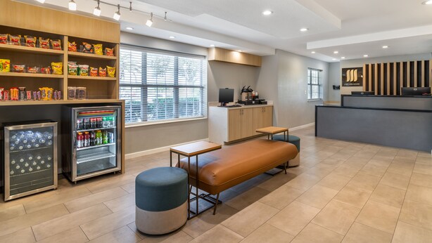 A modern hotel lobby with a seating area, snack vending machines, a refrigerator, and a reception desk. - MainStay Suites Houston NASA/Clear Lake (Houston)